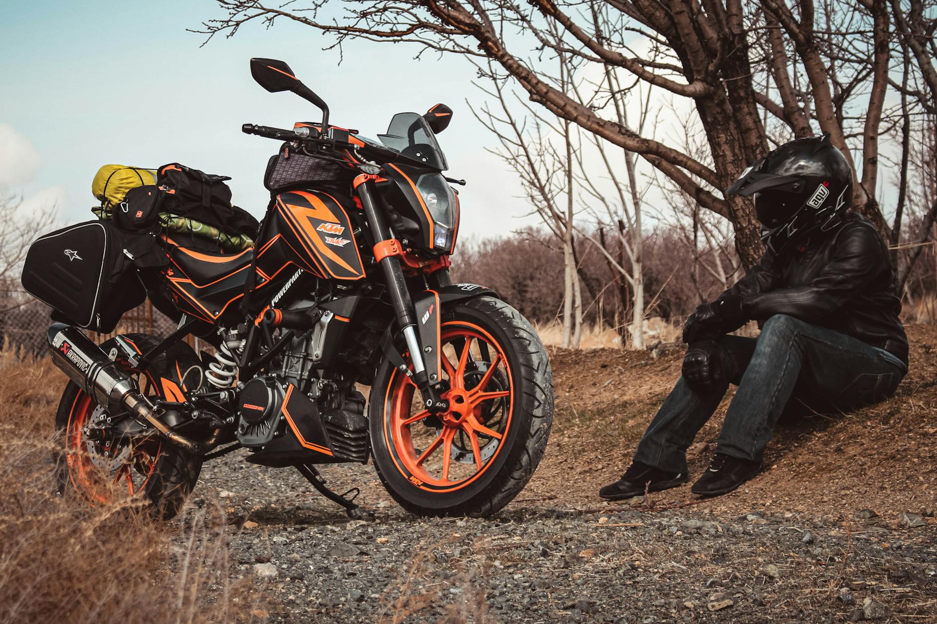 Motocyklista w turystycznym ubraniu odpoczywa przy załadowanym KTM na drodze