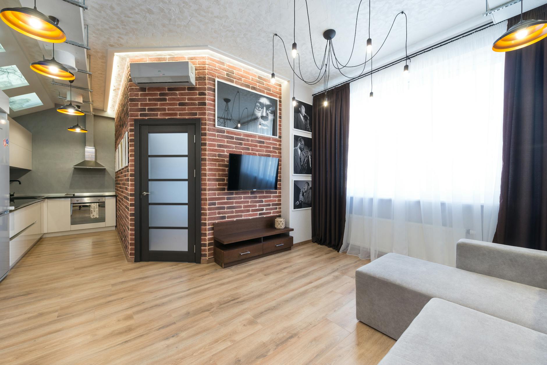 Nowoczesny salon loftowy z ceglaną ścianą i otwartym aneksem kuchennym