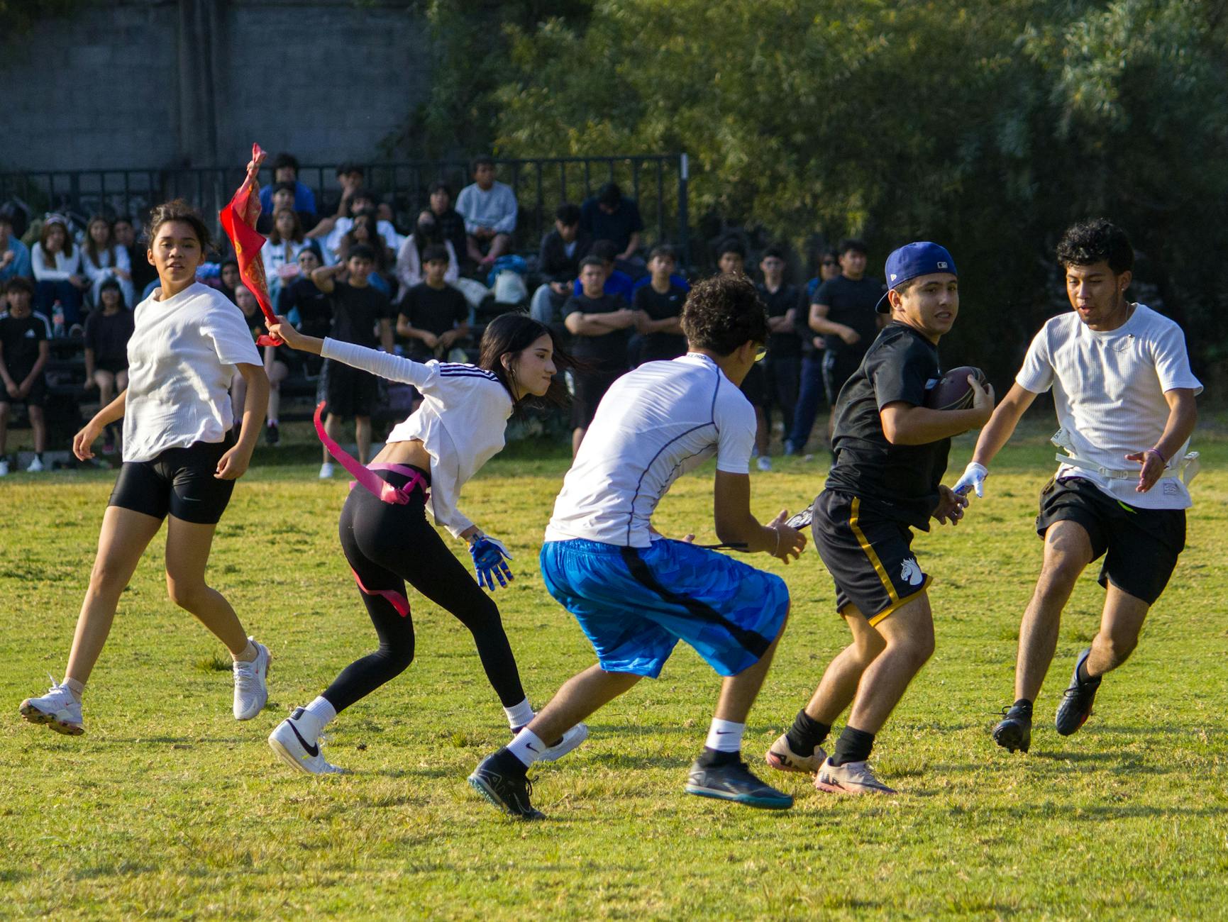 Studenci grają w flagowy futbol na boisku w słoneczny dzień
